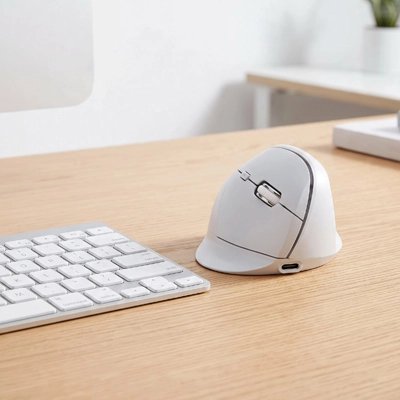 Souris ergonomique sans fil blanche près d'un clavier d'ordinateur