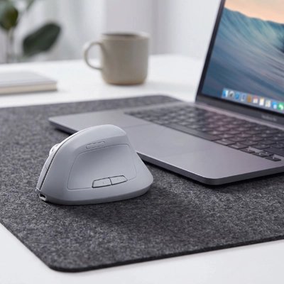 Souris ergonomique sans fil grise sur bureau de travail près d'un ordinateur portable