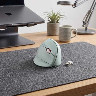 Souris ergonomique sans fil verte sur un sous-main de bureau avec un portable surélevé