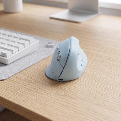 Souris ergonomique sans fil bleue près d'un clavier et d'un écran